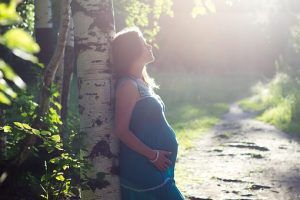 Depresión post Parto - chica apoyada en un árbol en actitud pensativa