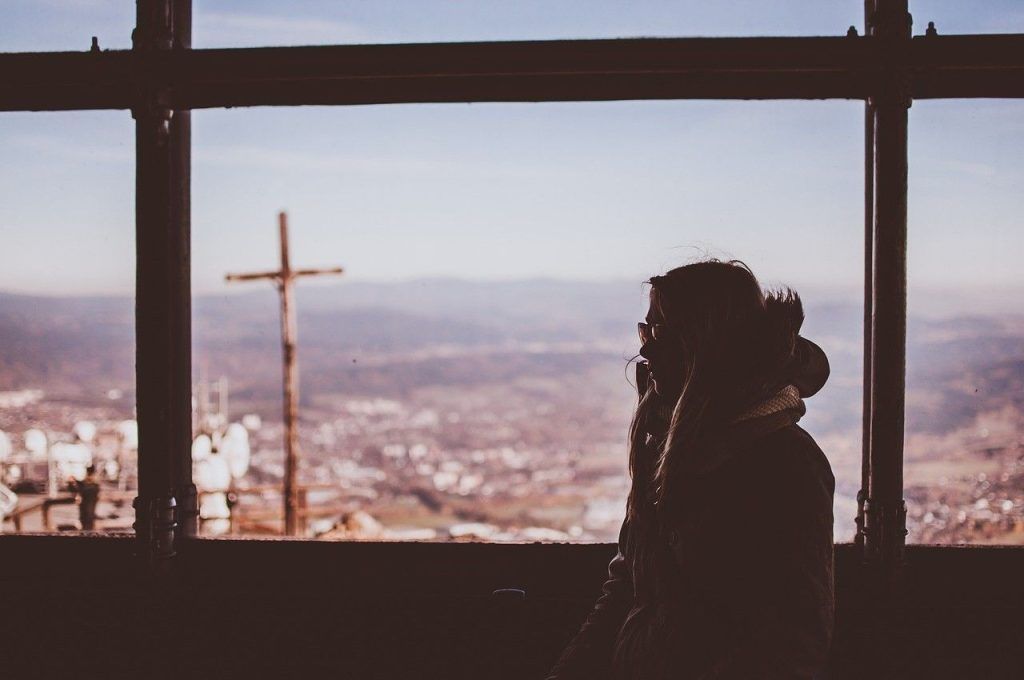 Imagen que contiene ventana, mujer, sentada, abrigo, azul, paisaje